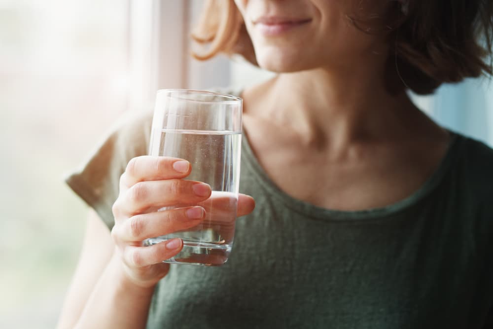 žena ispija čašu vode za pitanje kako prestati hrkati