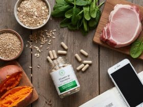 Prikaz zdravog stola s dodacima vitamina B1 i namirnicama poput mesa, povrća i žitarica, uz otvorenu knjigu "Vodič za B vitamine" za blog post o tiaminu.