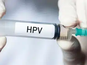 Medicinska štrcaljka s natpisom HPV u rukama zdravstvenog djelatnika, koja simbolizira cijepljenje protiv humanog papiloma virusa i prevenciju raka.