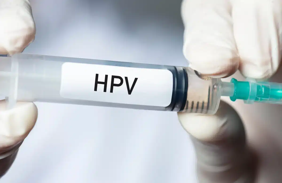 Medicinska štrcaljka s natpisom HPV u rukama zdravstvenog djelatnika, koja simbolizira cijepljenje protiv humanog papiloma virusa i prevenciju raka.
